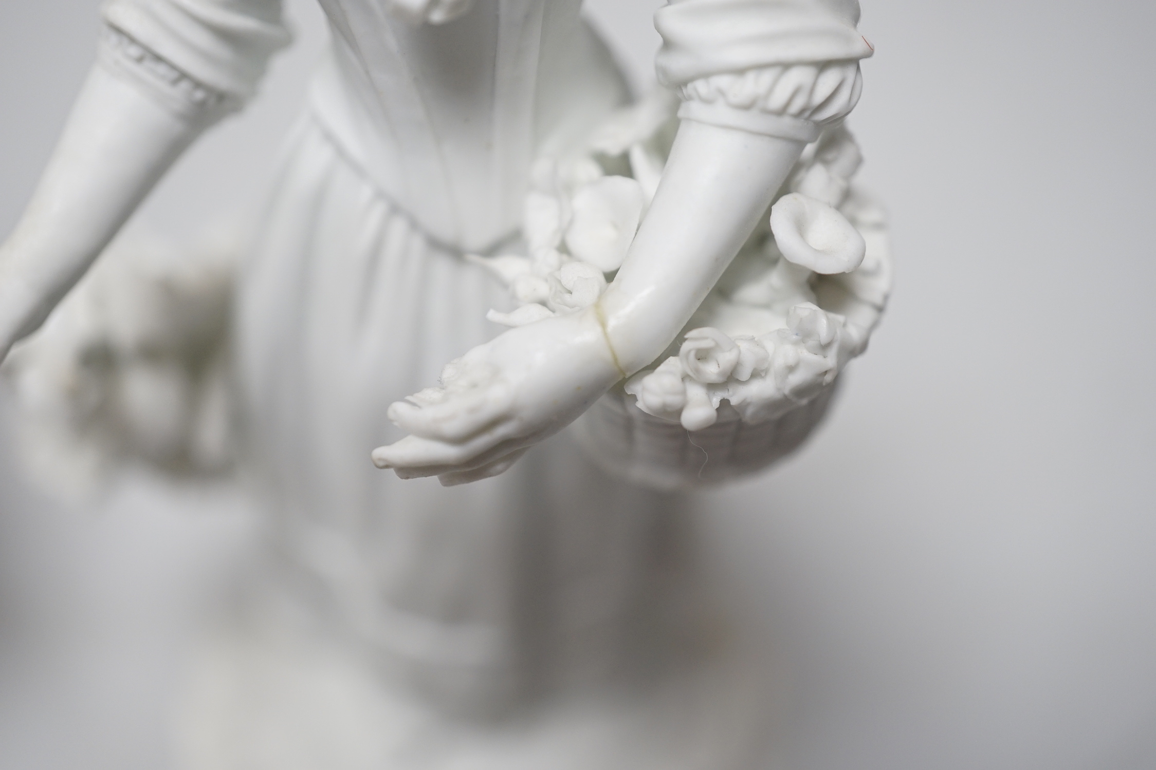 A pair of 18th century Derby biscuit figures of a man and woman, he with a bunch of grapes and she with a basket of flowers possibly representing Spring and Autumn, pattern number 125